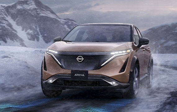 Nissan ARIYA in Sunrise Copper on snowy mountain road | Rydell Nissan of Grand Forks in Grand Forks ND