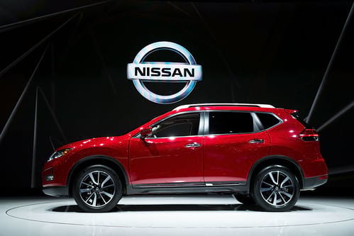 Red 2021 Nissan Sport profile view on show stage with Nissan logo in background