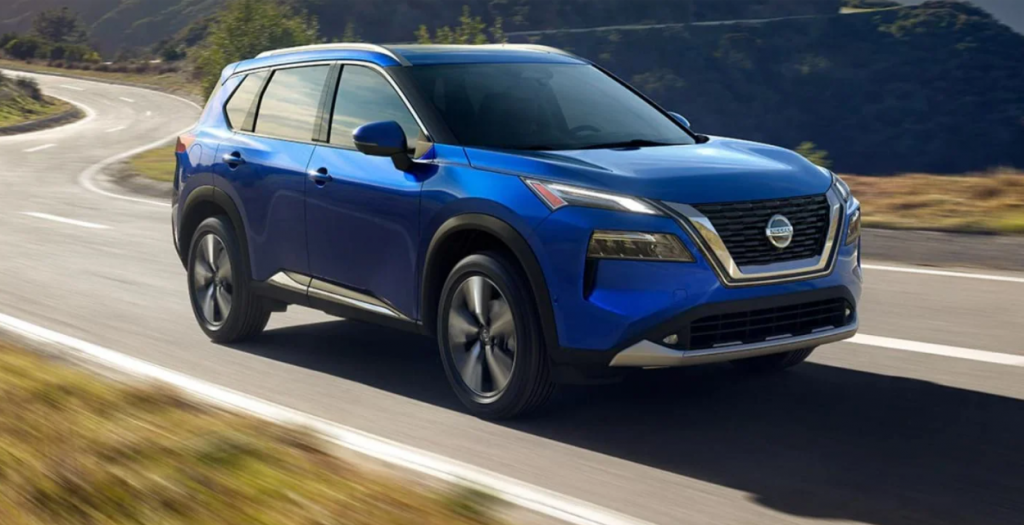 Blue Nissan Rogue driving on a winding road | Rydell Nissan of Grand Forks
